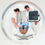 Doctor, nurse, and patient at CT scan tomography in hospital, shot through the tube of device
